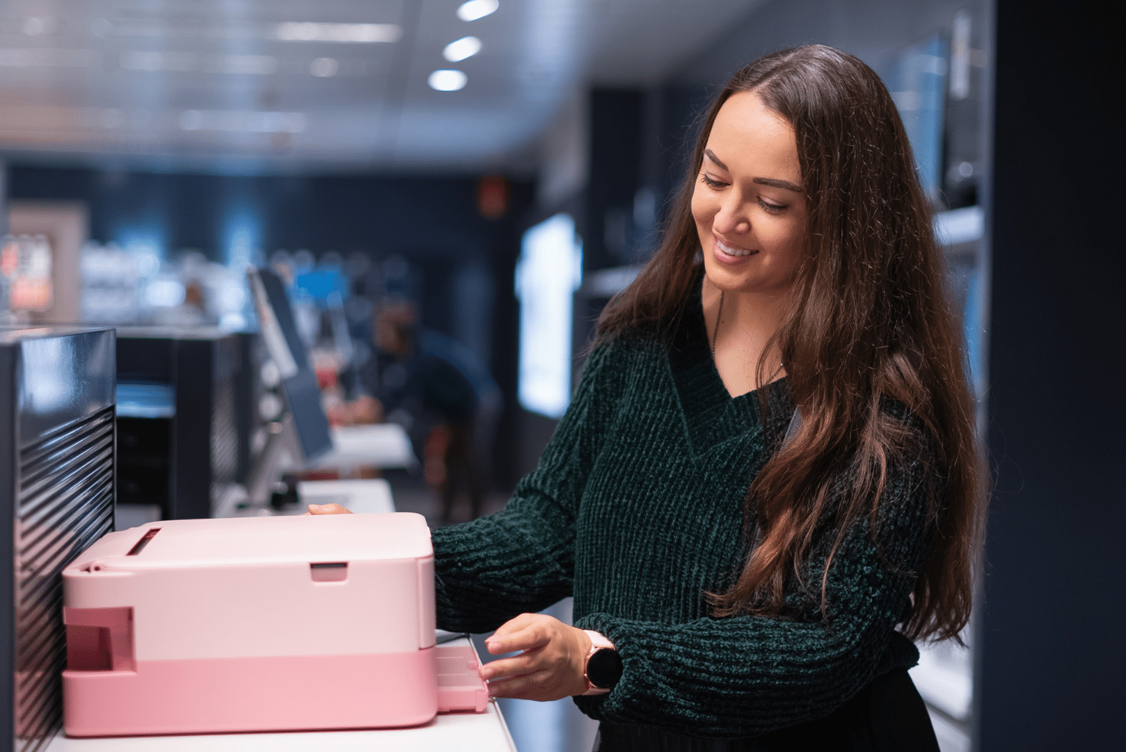 Smiling woman standing at a pink office fax machine